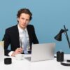 man sitting on chair beside laptop computer and teacup