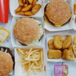 Top view flat lay of junk food including burgers with french fries and nuggets placed on marble table